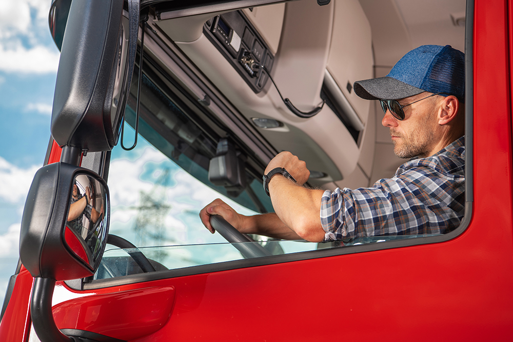 A truck driver in a red vehicle monitors his watch